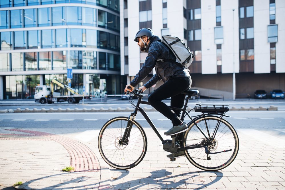 Male courier with bicycle delivering packages in city